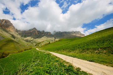 Fototapeta na wymiar Landscape with dirt road in the mountains under a cloudy sky