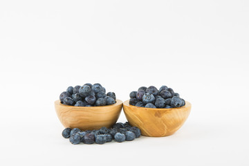 Two wooden bowls of blueberries on a white background