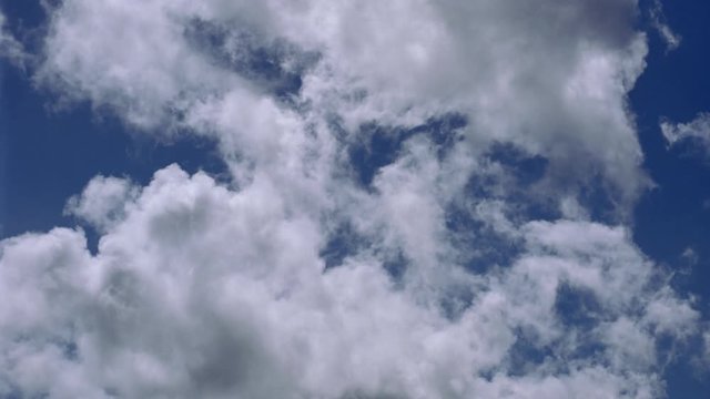 Ragged grayish time-lapse clouds drifting across blue sky