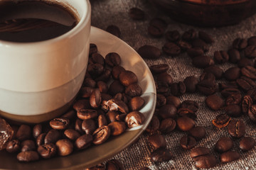 Cup on saucer with scattering of coffee beans and sugar