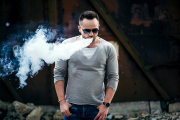 Vaper with beard in sunglasses vaping outdoor