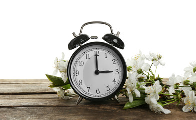 Alarm clock and spring blooming branches on wooden table