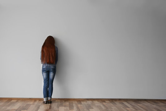 Family problems concept. Punished girl standing near wall