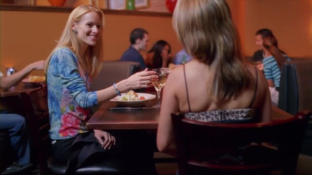 Young adults laughing and chatting while seated in a restaurant