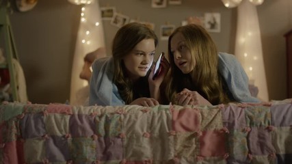 Medium shot of teenage girls talking on cell phone at sleepover / Cedar Hills, Utah, United States