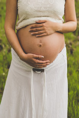 Fototapeta na wymiar Topless pregnant woman embracing her belly