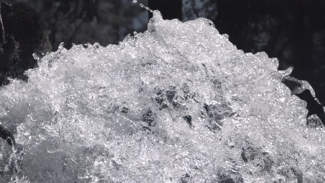 Close-up tilt-down on slow-motion water dropping over the top of a falls