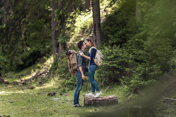Couple of hikers Hiking with backpacks walk along a beautiful mountain area, are kissing. The concept of romance and active rest