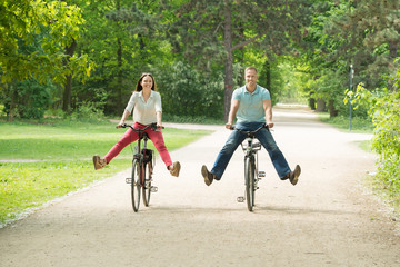 Obraz premium Happy Couple Riding Bicycle In Park