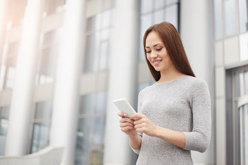 Business woman writing a message on the phone and smiling. Business concept.