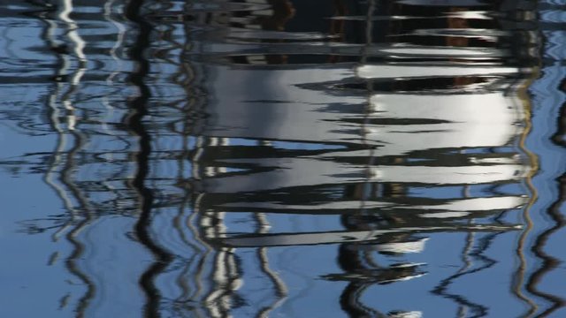 Reflected boat and masts in rippling harbor water
