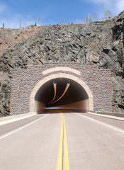 Road trip of a car traveling to a tunnel on route 61 a long the north shore of Lake Superior in...