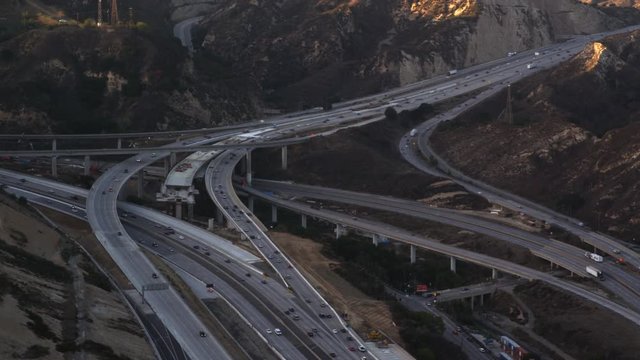 Flying over a complex freeway interchange in mountains near Los Angeles. Shot in 2010.