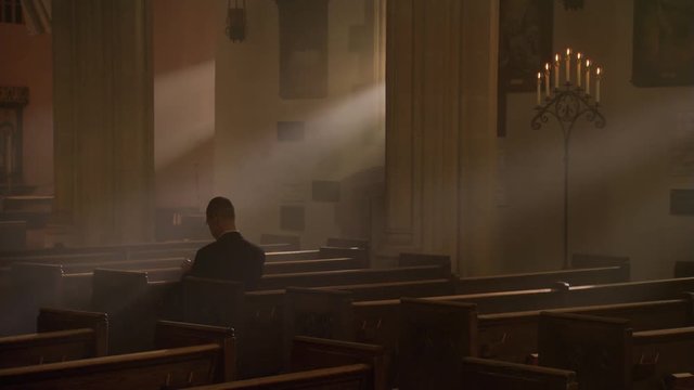 Man kneeling and praying in nave of Catholic church