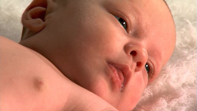Close-up face of drooling baby lying on fuzzy blanket