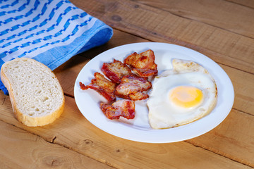 Fried egg with bacon, sliced bread and towel