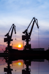 In the evening, the silhouette of port cranes