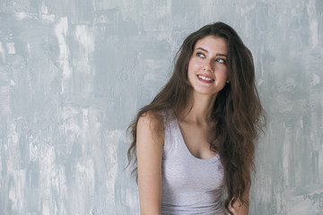 Fototapeta premium Dreaming brunette smiling up against of textured wall