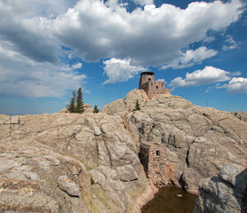 Fototapeta premium Harney Peak Fire Lookout Tower and pump house with small dam under cumulus clouds in Custer State Park in the Black Hills of South Dakota USA