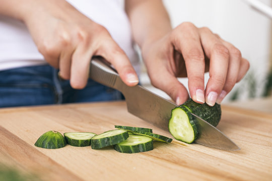 Close-up of woman cutting cucumber on board