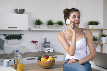 Portrait of young brunette woman looking away while talking on cell