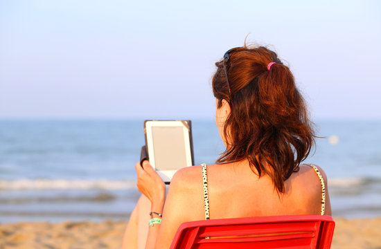 Pretty Woman On Red Chair Reads The Ebook On The Beach In Summer