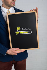Man in a suit with a black board in his hands on a white background.  Finance Idea Loading on Chalkboard