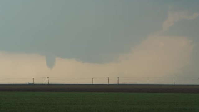 Funnel cloud about to become a tornado at the base of a wall cloud over farmland, time lapse