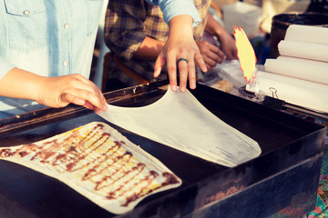 close up of cook frying pancakes at street market