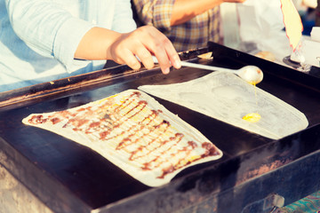 close up of cook frying pancakes at street market