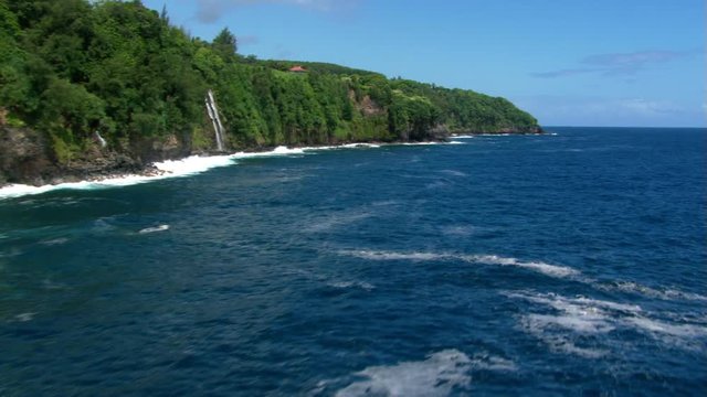 Low altitude flight over ocean near Hawaiian shoreline cliffs