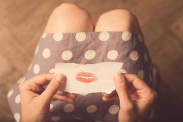 Woman hands holding a paper note with lipstick traces