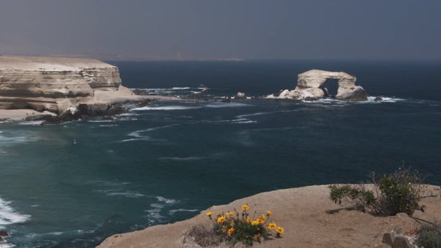 A natural arch in a sea stack near a barren headland
