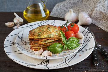 Vegetarian zucchini fritters served with fresh herbs, tomatoes a