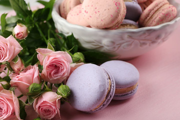 Obraz na płótnie Canvas Tasty macaroons with beautiful roses on pink background