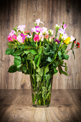 Bright flowers in the vase on wooden background