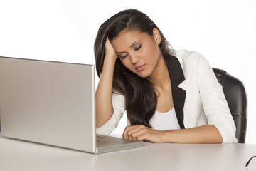 young tired business woman taking a nap on a desk with a laptop
