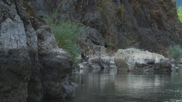 Drifting close past wall of Rogue River Canyon, Oregon; fish jumps near end of frame