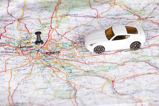 White toy car and a black pin on a map. Shallow depth of field.