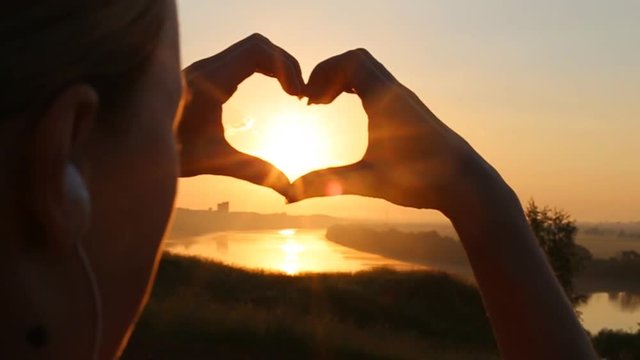 Sunset sun shining through heart shaped hands