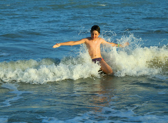 young boy plays by jumping the waves