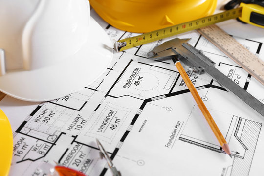 Construction blueprint with tools and helmets closeup