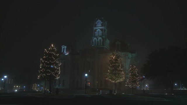 Lighted Christmas trees in front of a 19th Century civic building, zoom-in
