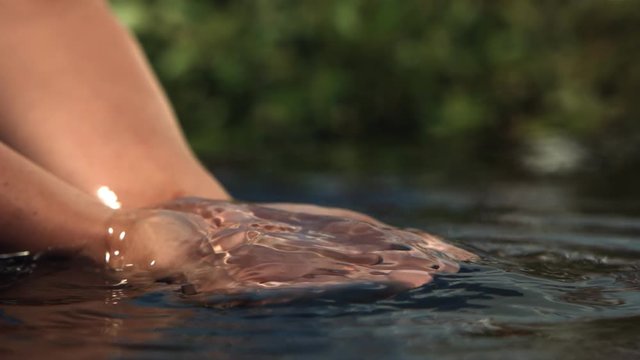 Close-up of cupped hands full of water trickling in ultra-slow motion