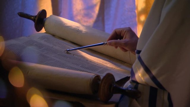Close-up of opened Torah, man's hand reading lines with stylus