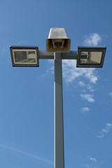 A vintage loudspeaker and modern light pole against the blue sky, vertical