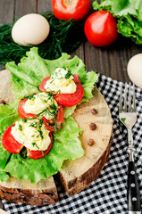 snacks , fresh tomatoes stuffed with eggs, melted cheese , mayonnaise and garlic with dill and lettuce on a wooden background