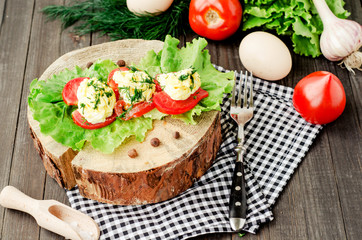 snacks , fresh tomatoes stuffed with eggs, melted cheese , mayonnaise and garlic with dill and lettuce on a wooden background
