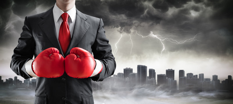 Businessman In Boxing Gloves With Cityscape In The Storm
