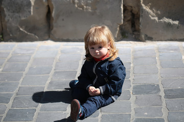 Little boy sits on pavement